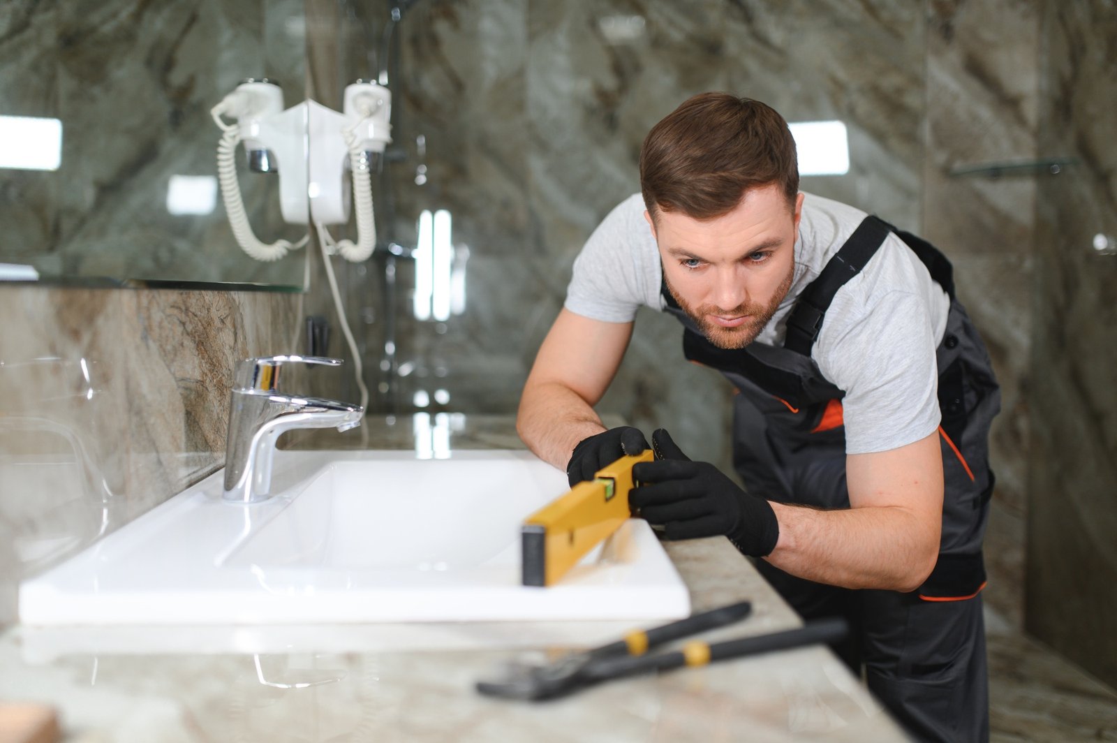 Plumber install sink in bathroom, checks even level of installation. Concept repair service plumbing